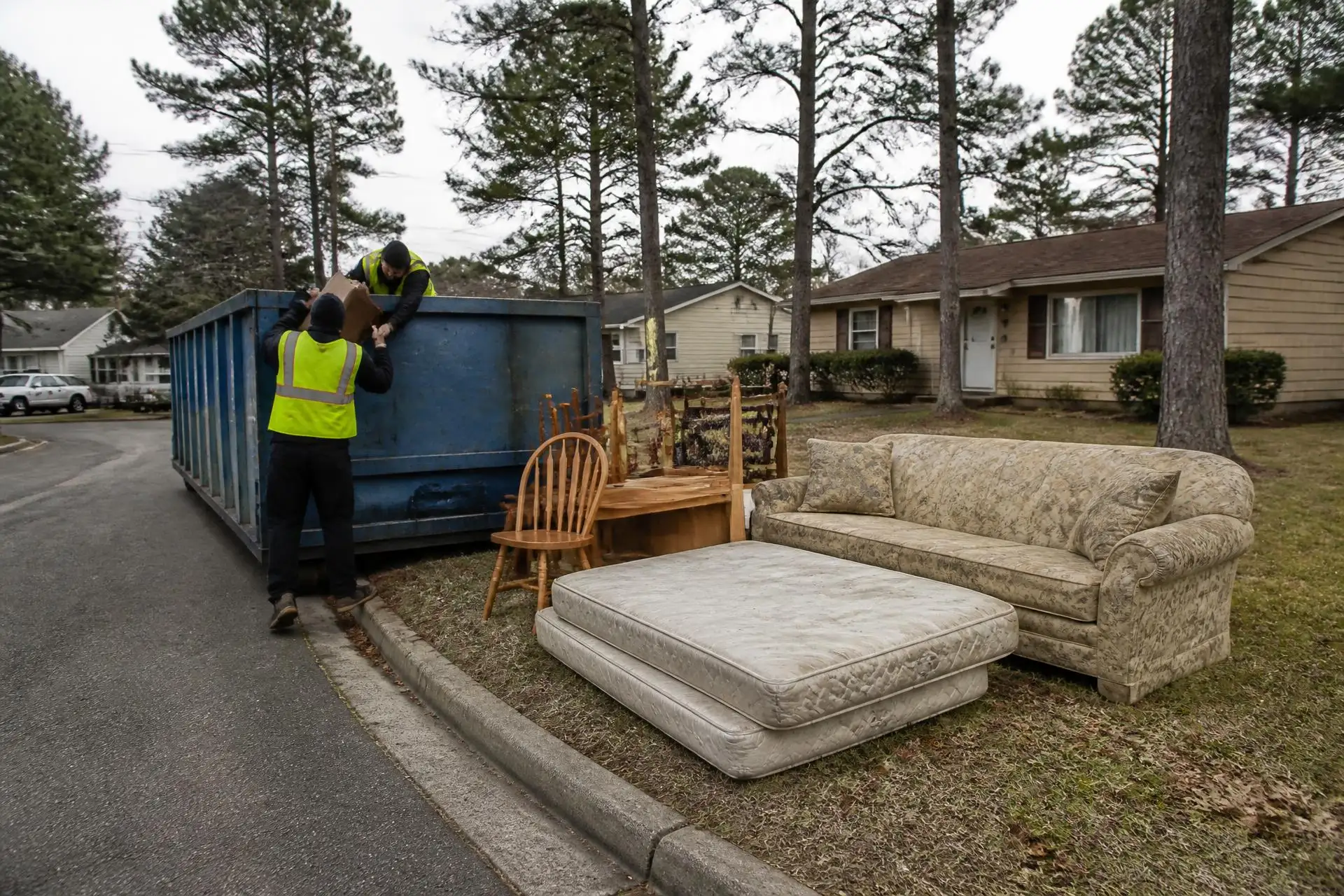 Crew loading an old couch and mattresses from a Manchester, NJ curb into a roll-off dumpster