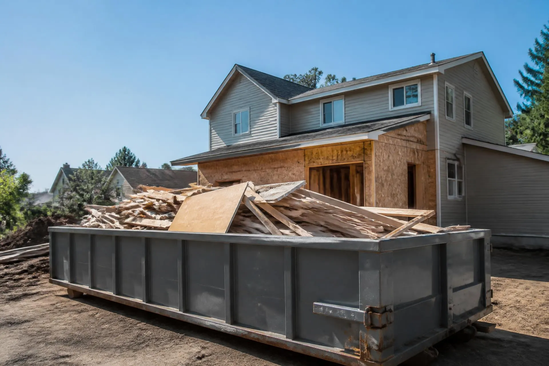 Construction and demolition debris loaded into a large roll-off container at a renovation site