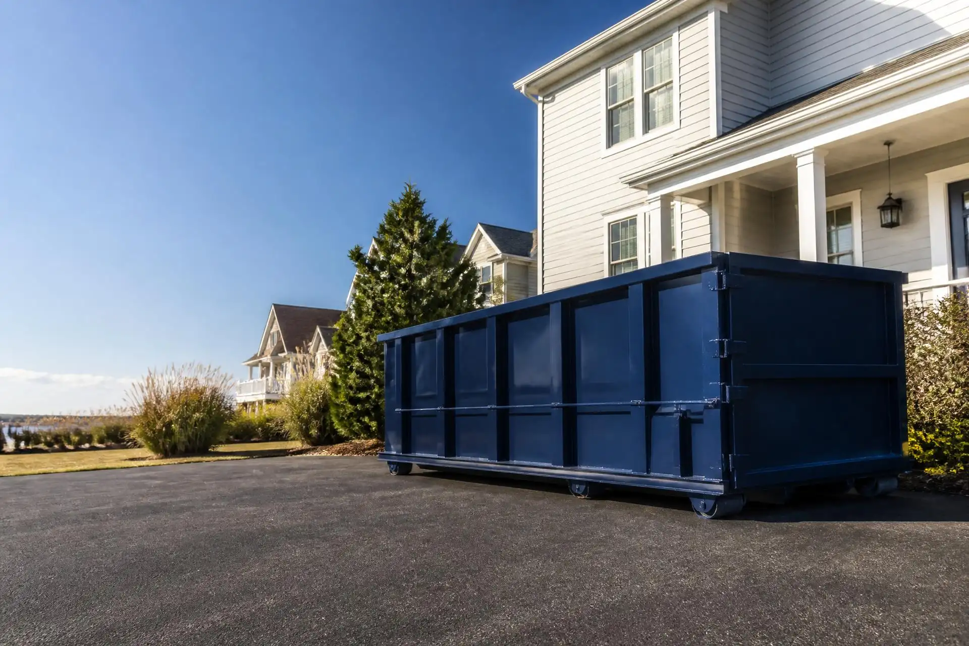 Blue roll-off dumpster set on a suburban driveway in Manchester, NJ, ready for loading